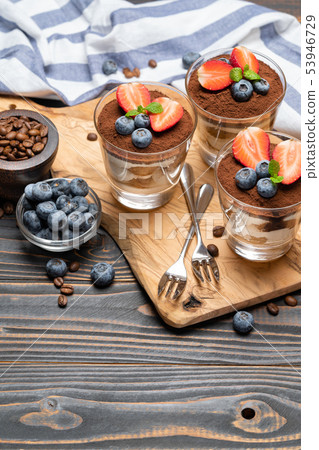 Classic tiramisu dessert with blueberries and strawberries in a glass on wooden background 53946729