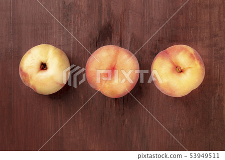 Vibrant organic flat saturn peaches, shot from above on a dark rustic wooden background with a place 53949511