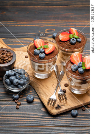 Classic tiramisu dessert with blueberries and strawberries in a glass on wooden background Classic tiramisu dessert with blueberries and strawberries in a glass on wooden background 53952637