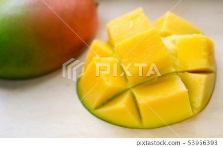 Ripe juicy yellow exotic mango cut into cubes on wooden background. Tropical delicacy full of 53956393