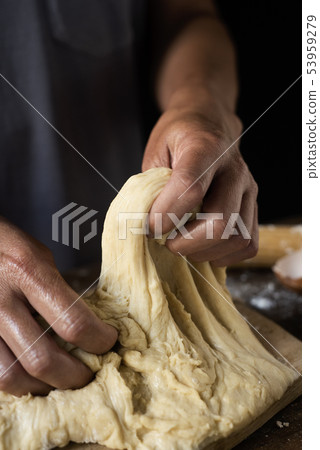 young man kneading a piece of dough young man kneading a piece of dough 53959279