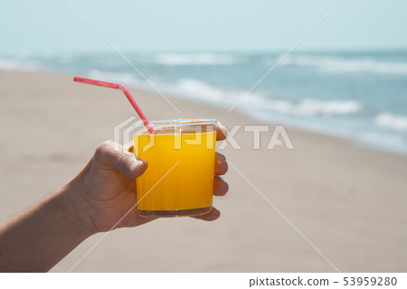 man having an orange drink on the beach. 53959280