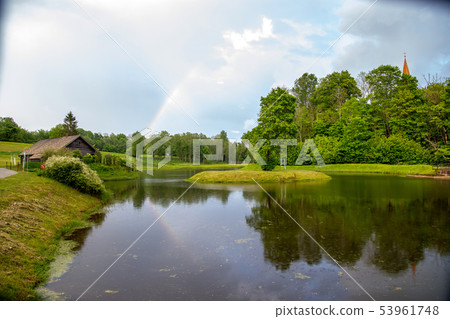 Rainbow over the trees and pond 53961748