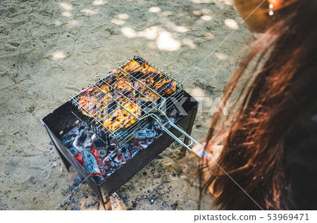 Woman hold a grid of grill with chicken meat Woman hold a grid of grill with chicken meat 53969471