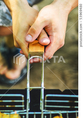 Man hold a grid of grill with chicken meat Man hold a grid of grill with chicken meat 53969480