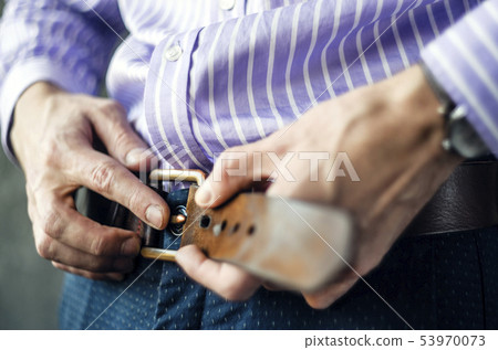 Young Man Puts on a Belt in Trousers Close Up Young Man Puts on a Belt in Trousers Close Up 53970073
