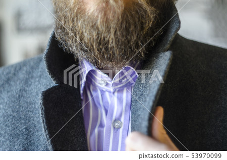 Man Adjusting Collar in Gray Coat Close-Up 53970099