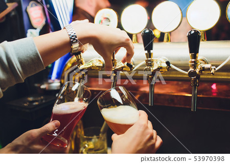 Hand of bartender pouring a large lager beer in tap. Hand of bartender pouring a large lager beer in tap. 53970398