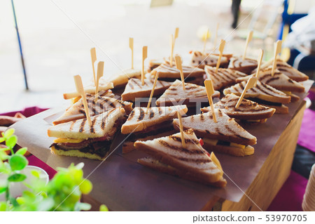 Cut platter of mixed sandwich triangles, on the buffet table. 53970705