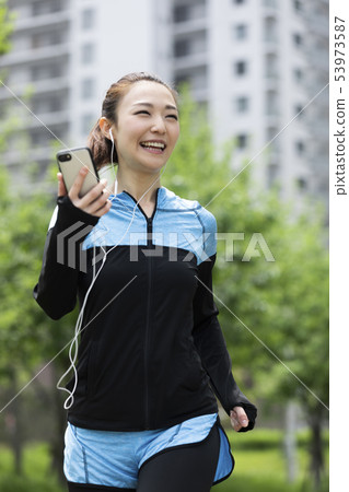 A woman running while listening to music A woman running while listening to music 53973587