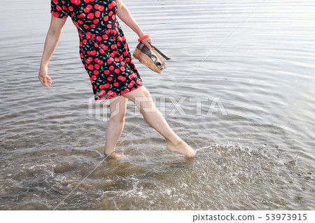 Woman kicking water 53973915