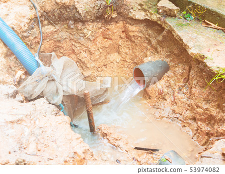 broken pipe in hole with water motion at roadside 53974082