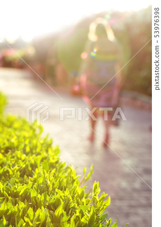 Woman walking away in summer evening glow Woman walking away in summer evening glow 53976398
