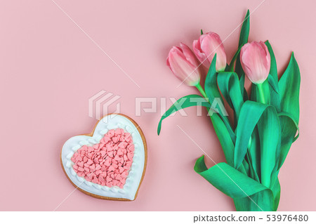 Heart shaped cookie and tulips on pink Heart shaped cookie and tulips on pink 53976480