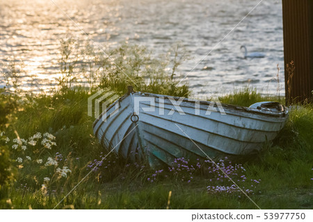 Old white rowing boat on land by sunset Old white rowing boat on land by sunset 53977750