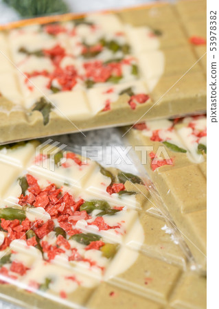 Handmade chocolates bar. Christmas theme. White chocolate bar with pistachio nuts and dried fruit Handmade chocolates bar. Christmas theme. White chocolate bar with pistachio nuts and dried fruit 53978382