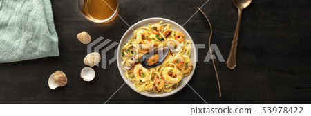 Seafood pasta panorama. Tagliolini with mussels, shrimps, clams and squids, with a glass of white Seafood pasta panorama. Tagliolini with mussels, shrimps, clams and squids, with a glass of white 53978422