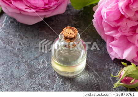 A bottle of rose essential oil with rose flowers A bottle of rose essential oil with rose flowers 53979761