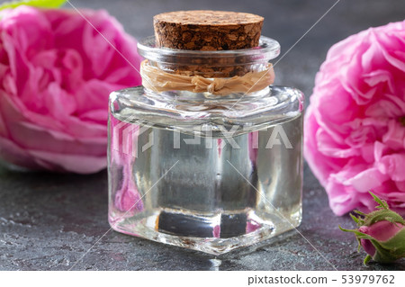 A bottle of rose essential oil with rose flowers A bottle of rose essential oil with rose flowers 53979762