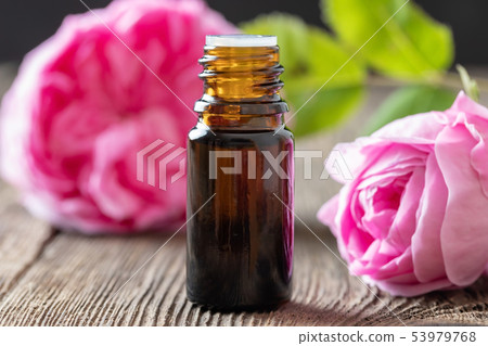 A bottle of rose essential oil with rose flowers 53979768