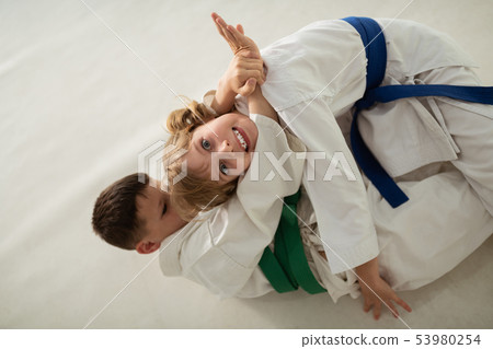 Girl making funny face having aikido battle with friend Girl making funny face having aikido battle with friend 53980254