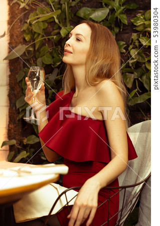 A beautiful young woman in an asymmetrical red A beautiful young woman in an asymmetrical red 53980304