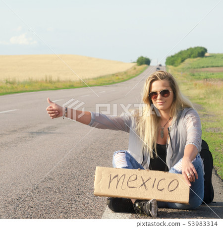 Beautiful Girl Hitchhiking On The Road Traveling. 53983314