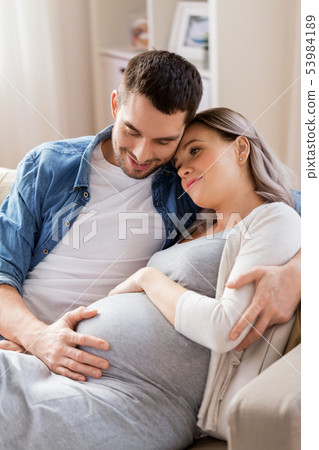man hugging pregnant woman at home 53984189