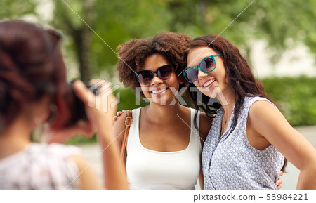 woman photographing her friends in summer park woman photographing her friends in summer park 53984221