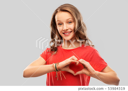 smiling teenage girl in red making hand heart 53984319