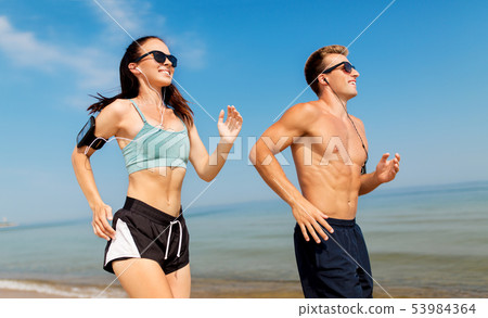 couple with phones and arm bands running on beach couple with phones and arm bands running on beach 53984364