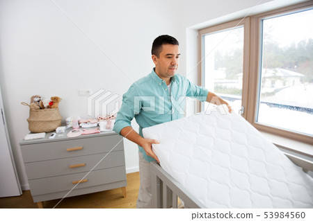 father arranging baby bed with mattress at home father arranging baby bed with mattress at home 53984560