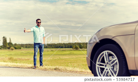 man hitchhiking and stopping car at countryside man hitchhiking and stopping car at countryside 53984717