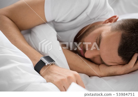 close up of man with smart watch sleeping in bed 53984751