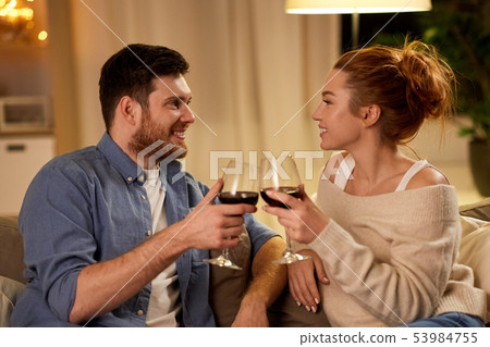 happy couple drinking red wine at home in evening happy couple drinking red wine at home in evening 53984755