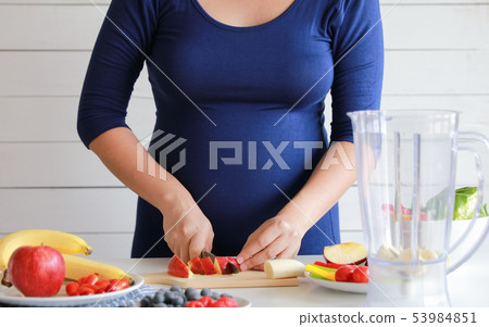 pregnant woman cooking and cutting fruit for fruit pregnant woman cooking and cutting fruit for fruit 53984851