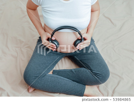 pregnant woman listen to music with headphone pregnant woman listen to music with headphone 53984865