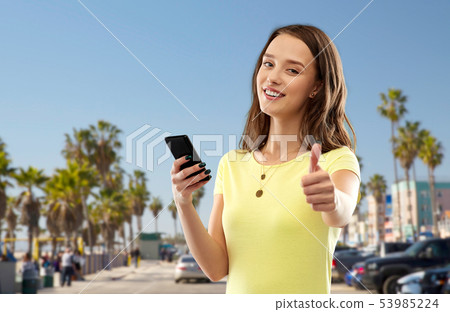 teenage girl with smartphone showing thumbs up 53985224