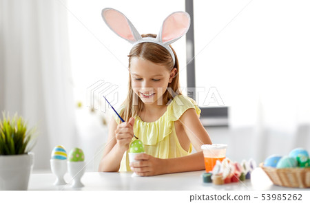 happy girl coloring easter eggs at home 53985262