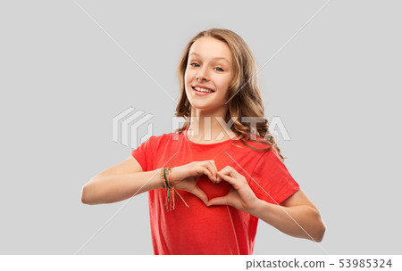 smiling teenage girl in red making hand heart 53985324