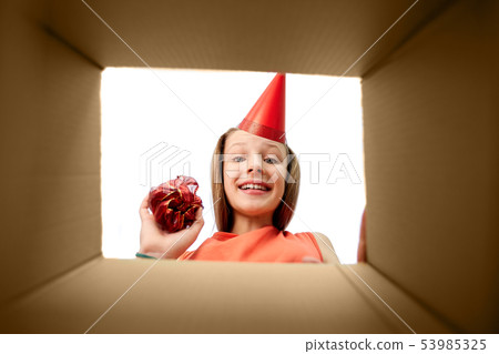 birthday girl in party hat looking into gift box birthday girl in party hat looking into gift box 53985325