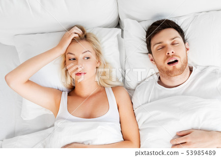 unhappy woman in bed with snoring sleeping man unhappy woman in bed with snoring sleeping man 53985489