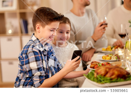 boy with sister using smartphone at family dinner 53985661