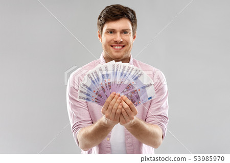 smiling young man with fan of euro money over grey 53985970