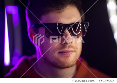 man in sunglasses over ultra violet neon lights 53986002