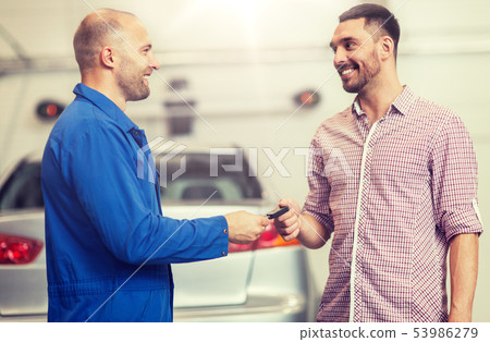 auto mechanic giving key to man at car shop 53986279