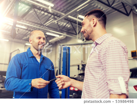 auto mechanic giving key to man at car shop 53986498