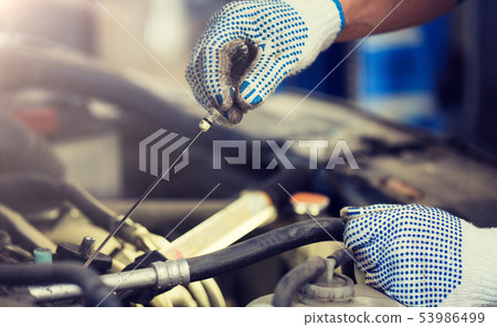 mechanic with dipstick checking motor oil level 53986499
