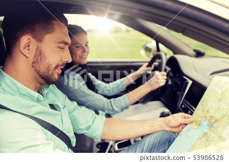 happy man and woman with road map driving in car 53986528