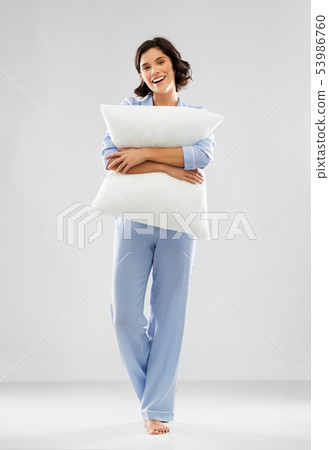 happy young woman in blue pajama hugging pillow happy young woman in blue pajama hugging pillow 53986760